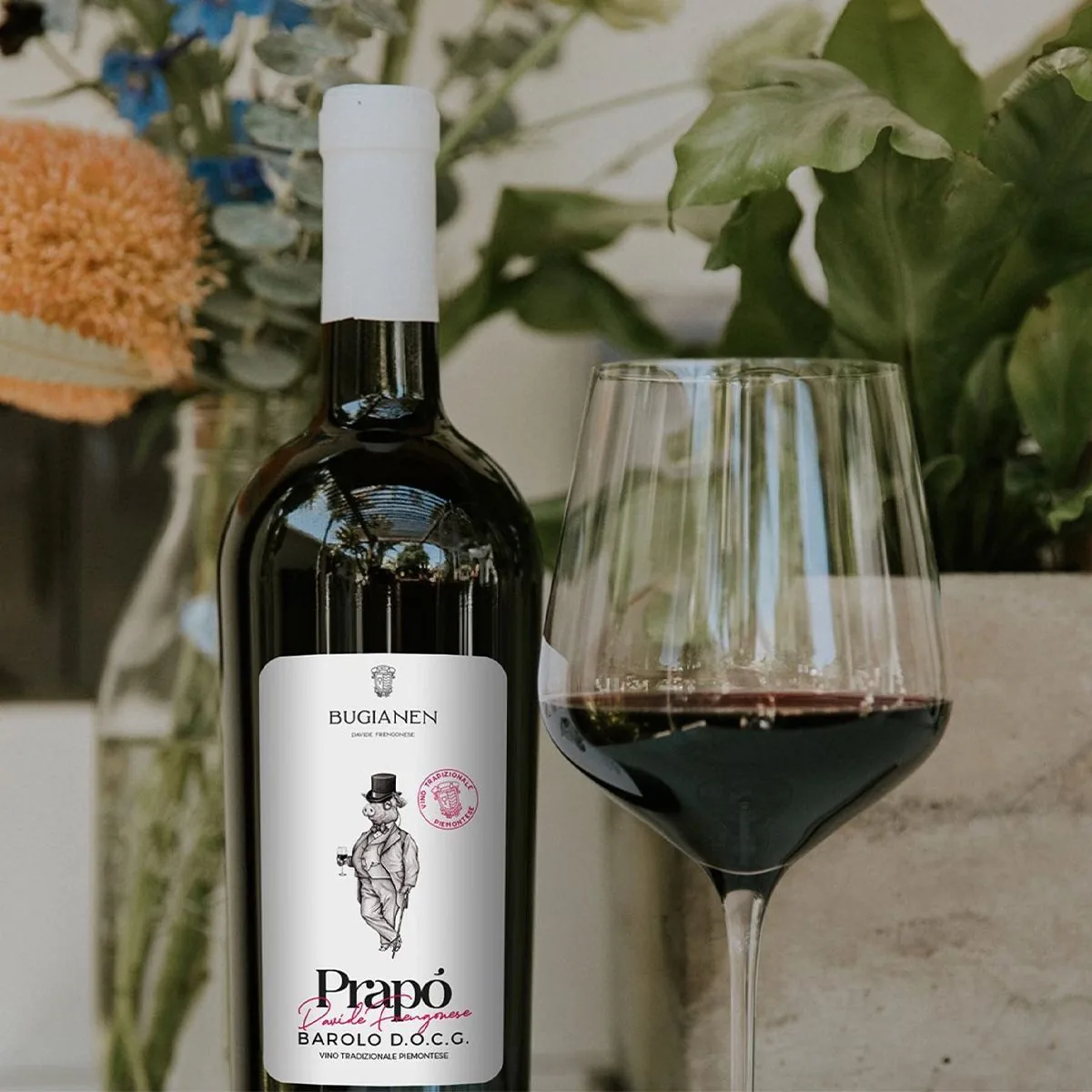 Bottiglia Bugianen con etichetta illustrata e calice di vino rosso